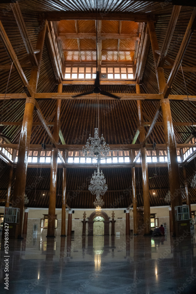 Fototapeta premium Interior view of Masjid Agung Surakarta, showcasing grand chandeliers, traditional wooden pillars, and serene architecture.