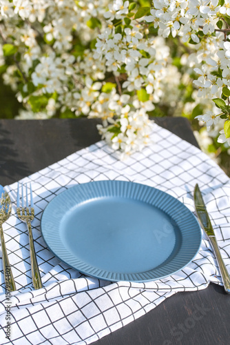 Elegant spring table setting with blue plate and floral background
