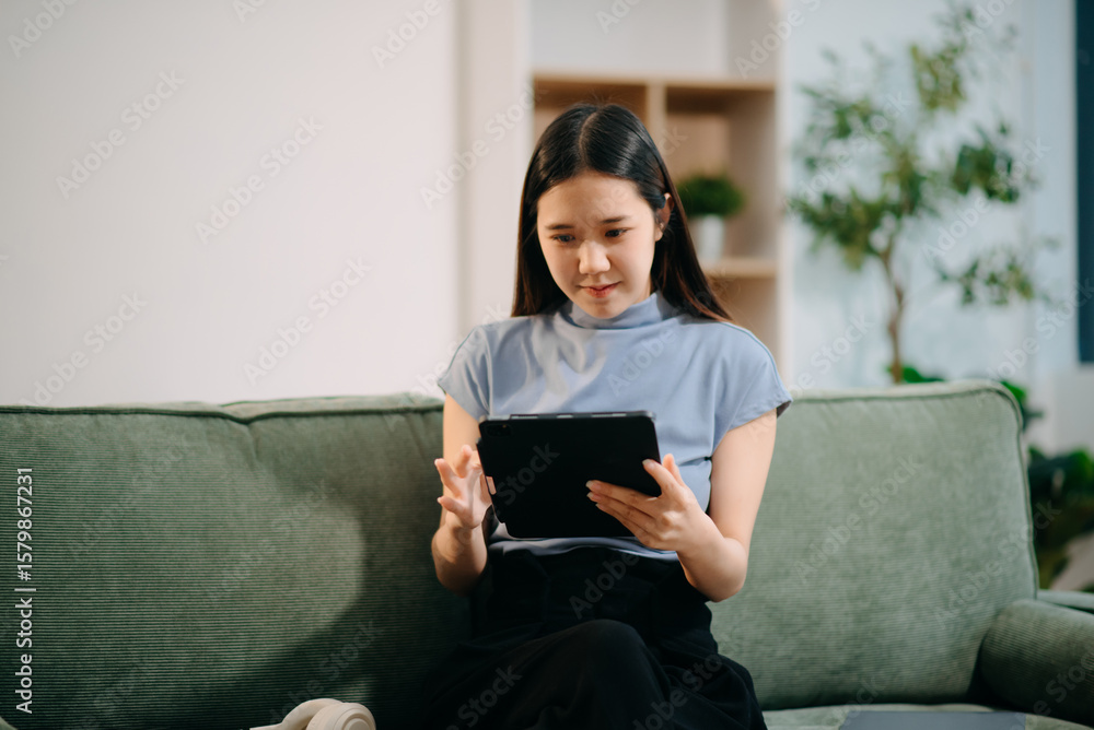 Obraz premium Young asian woman relax on comfortable couch at home texting messaging on smartphone and tablet