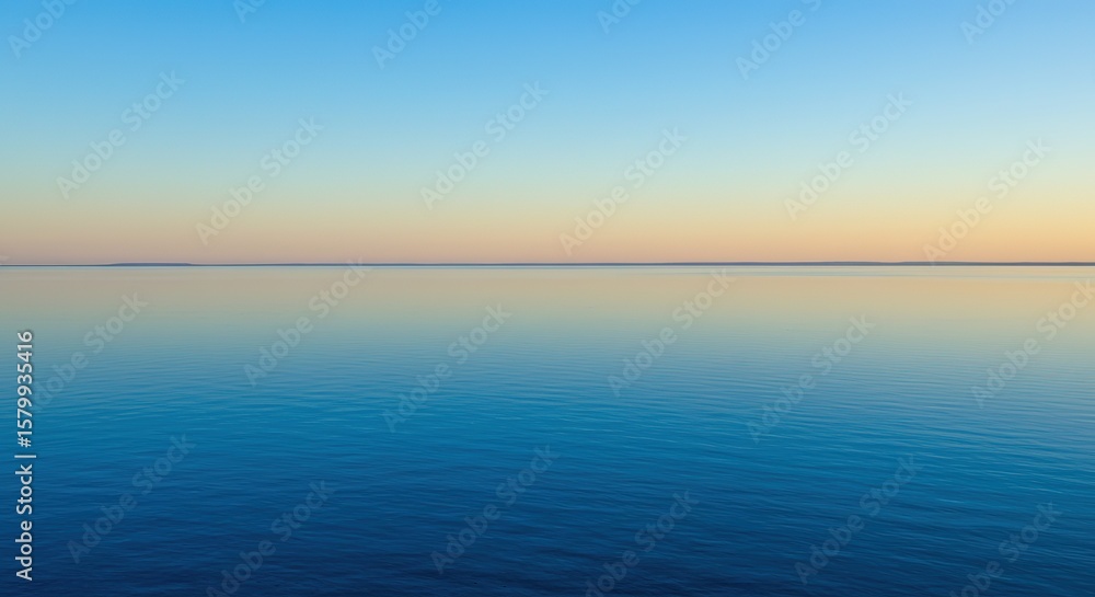 Obraz premium Calm water reflects a gradient sky with blue orange and yellow colors.