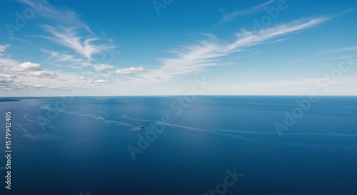 Calm ocean water stretches to the horizon under a blue sky with clouds.