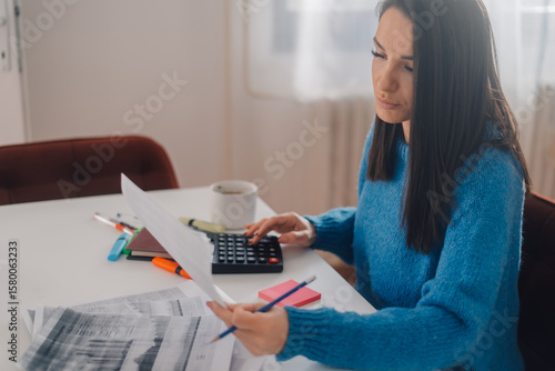 Accountant calculating domestic bills at home office using calculator and checking receipts
