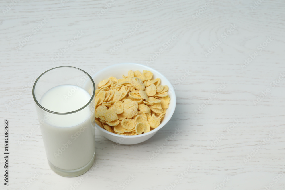 glass with milk, cornflakes on white wooden background glass with milk, cornflakes on white wooden background