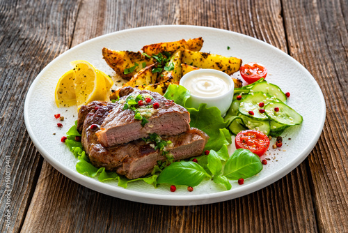 Wallpaper Mural Grilled beef steak with baked potato wedges and fresh vegetables on wooden table	 Torontodigital.ca