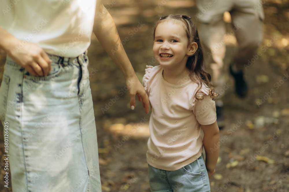Smiling Little Girl Outdoors With Family in a Summer Park Setting Smiling Little Girl Outdoors With Family in a Summer Park Setting