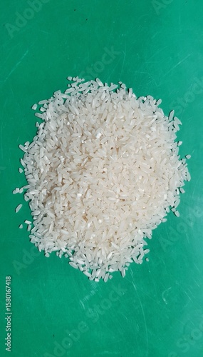 A pile of dry white rice with a turquoise green background
