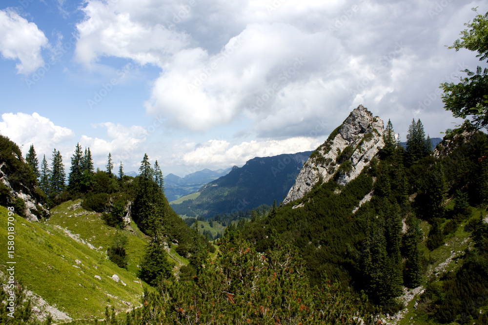 Obraz premium Serene mountain landscape in Tyrol, Austria showcasing lush greenery and dramatic rock formations under a partly cloudy sky