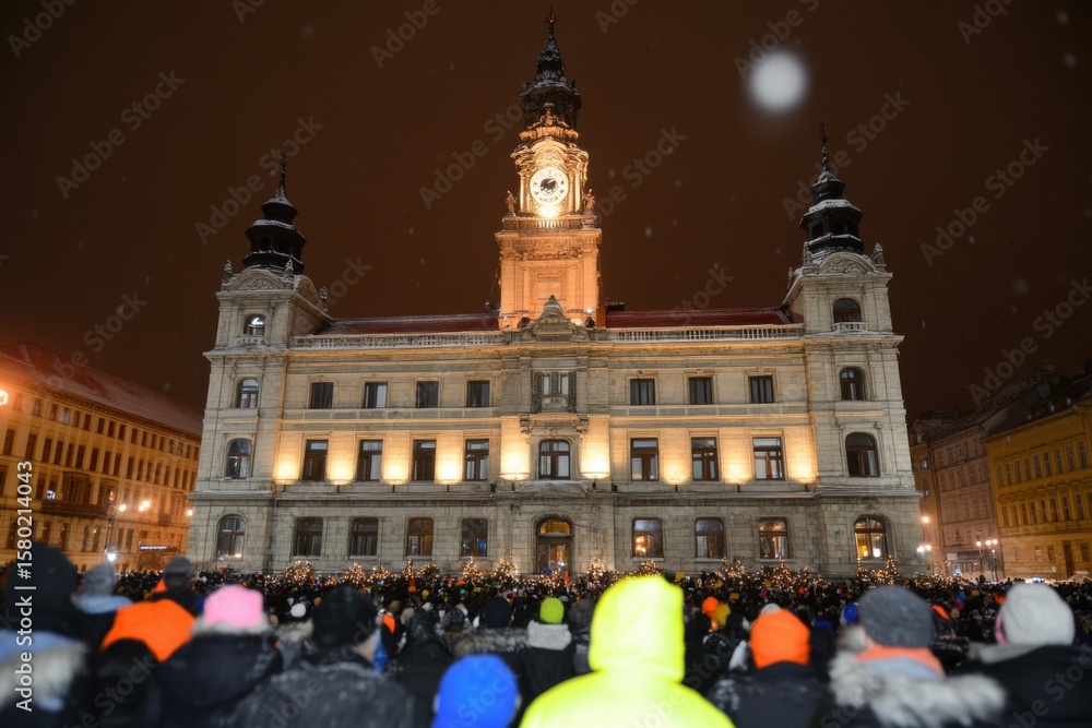 Naklejka premium Town Hall Gathering: A majestic town hall illuminated against a night sky, its architectural grandeur and central clock tower providing a sense of place and history amidst a vibrant gathering.