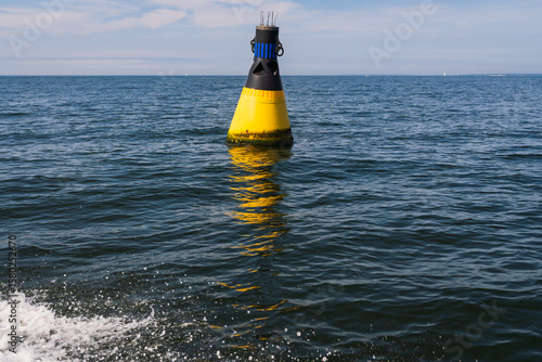 Fototapeta Naklejka Na Ścianę i Meble -  A North Cardinal Mark, a yellow and black navigational buoy, floating in the open blue sea to provide safety and guidance for passing ships.