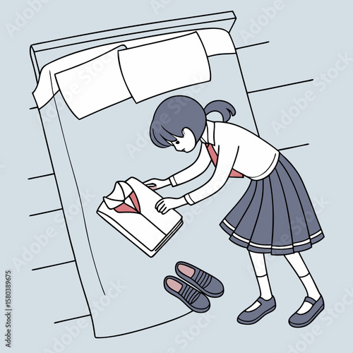 Girl in school uniform folding clothes on bed with pillows and slippers on the floor in a bedroom scene