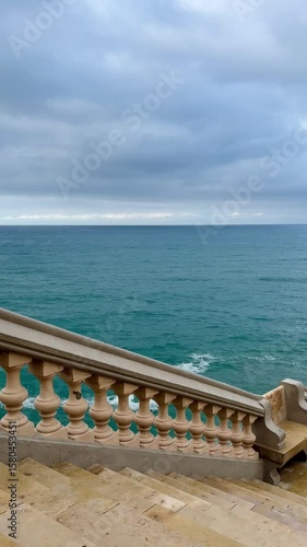 Cinematic view of a moody sea framed by the balustrade of Sitges cathedral stairs