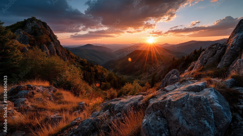 Obraz premium A mesmerizing sunset casting vibrant hues over mountain ranges, with misty valleys below. The light dances on the peaks, creating a tranquil and awe-inspiring atmosphere. 