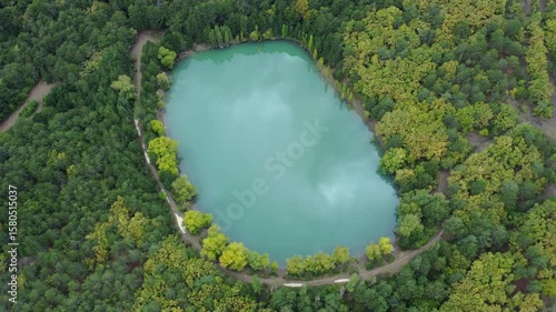 Aerial view over a turquoise lake, with a reflection of the passing clouds