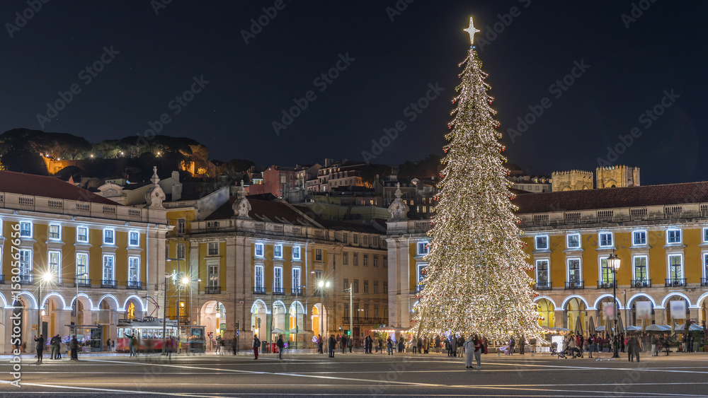Obraz premium Commerce Square in Lisbon illuminated at Christmas hyperlapse, with a towering tree and crowds celebrating at night. Portugal