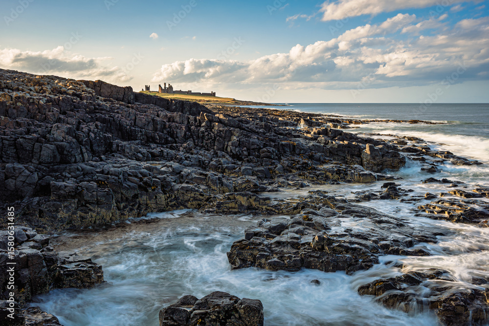 Obraz premium The rocky shore south of Dunstanburgh Castle. The rocky shore between Craster Village and Dunstanburgh Castle is an ever changing tidal environment in Northumberlands National Landscape