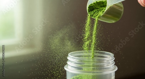 Pouring green powder into a container with a soft background.