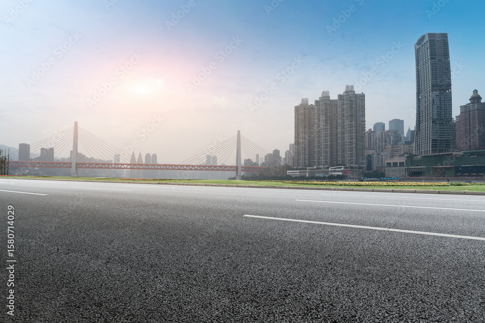 Naklejka premium Urban road with modern buildings and bridge in the background