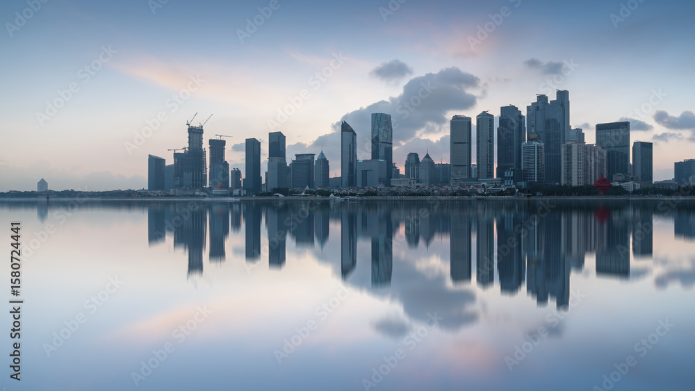 Obraz premium City skyline with calm water reflection at dawn