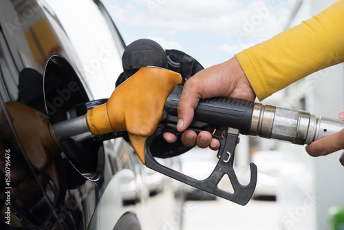Wallpaper Mural Hand holding fuel nozzle pumping gasoline into car at gas station close up showing refueling and energy concept Torontodigital.ca