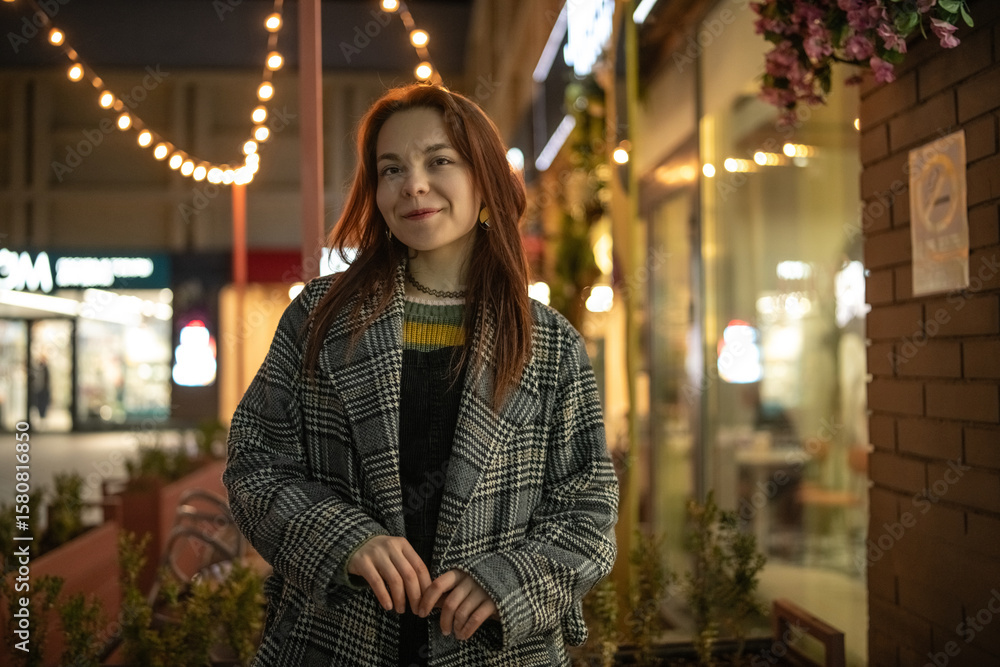 Obraz premium Portrait of a young beautiful cheerful red-haired girl in an evening autumn city.