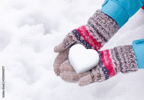 Hands in knitted mittens with heart shaped snow. Winters Day. Valentine's Day