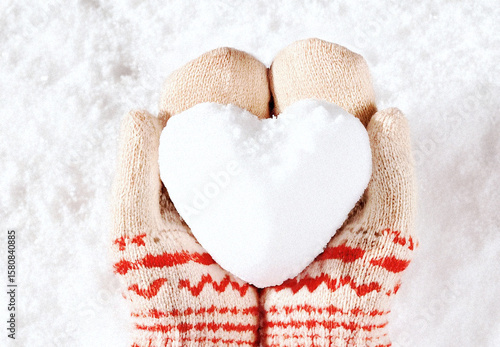 Hands in knitted mittens with heart shaped snow. Winters Day. Valentine's Day