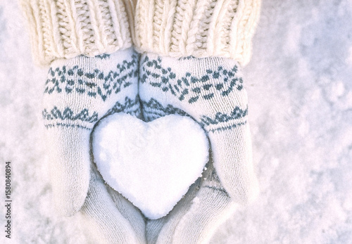 Hands in knitted mittens with heart shaped snow. Winters Day. Valentine's Day