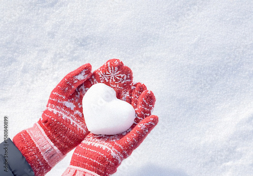 Hands in knitted mittens with heart shaped snow. Winters Day. Valentine's Day