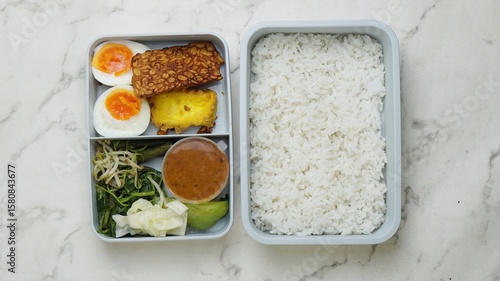 rice, egg and vegetables in lunch boxes with food ready to go for work or school, bento