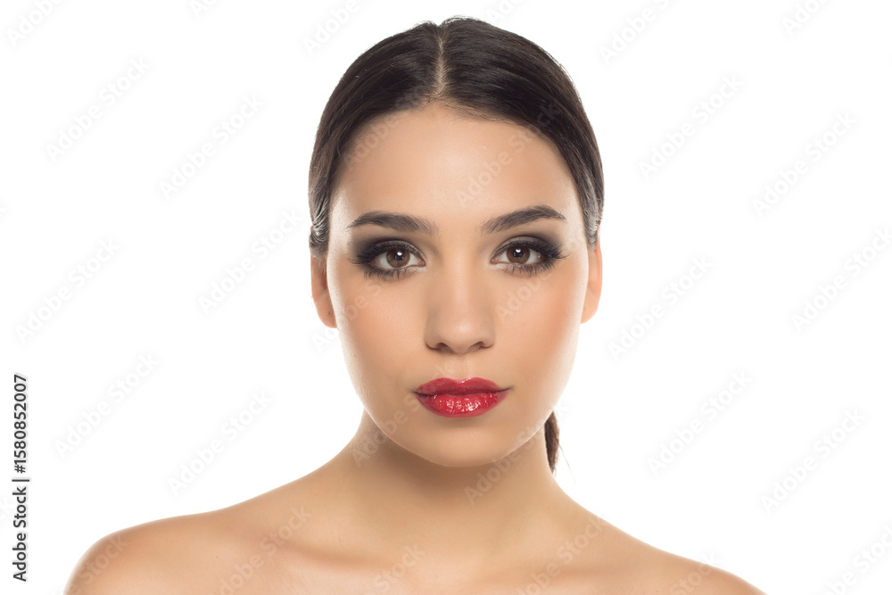 Portrait of young woman with glamorous makeup and red lipstick, looking confidently at camera, studio shot on white background. Portrait of young woman with glamorous makeup and red lipstick, looking confidently at camera, studio shot on white background.
