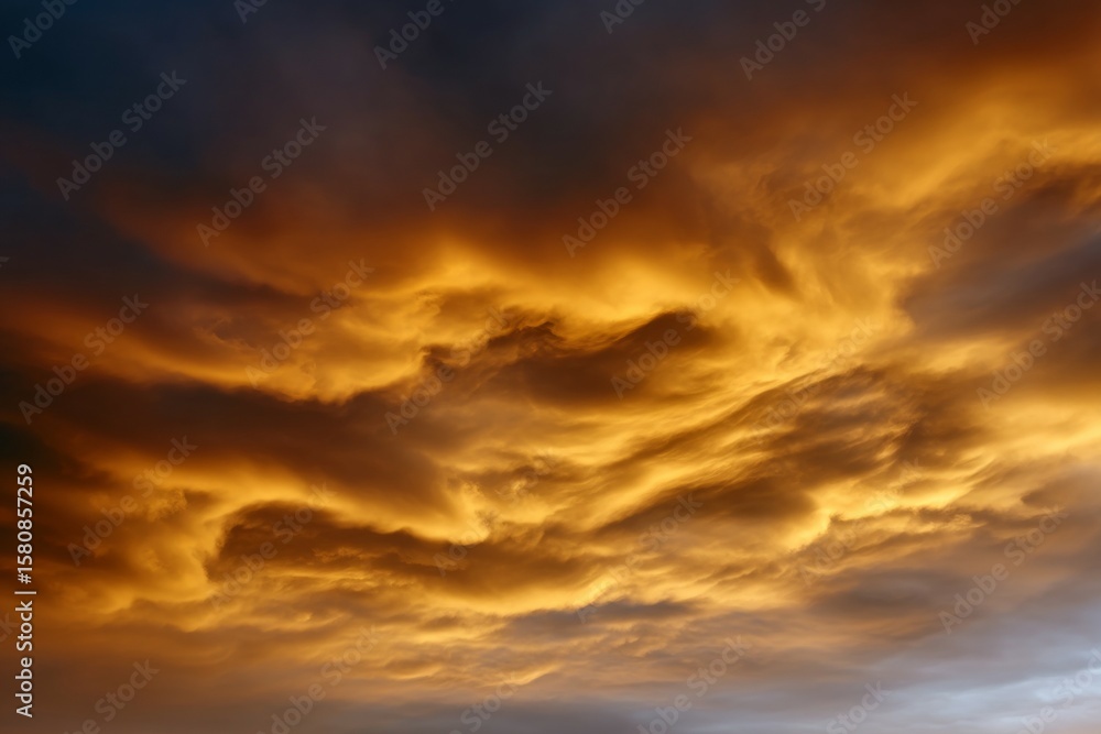 Fototapeta premium Fiery orange clouds in dramatic sky at sunset