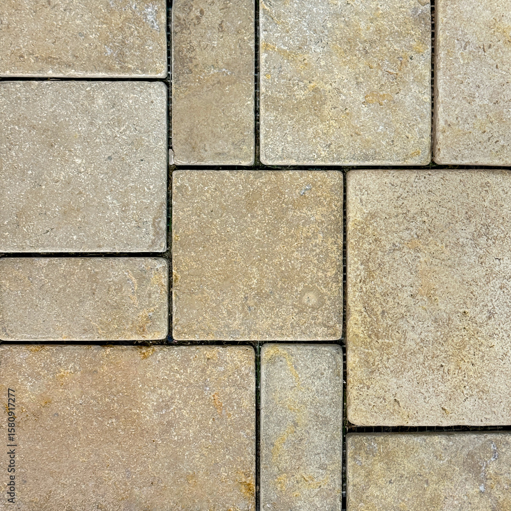 Obraz premium Natural beige stone marble tiles in square and rectangular pattern. Outdoor textured honed tiles in yellow and beige color with black grouts. Wall or floor tiles seamless background texture.