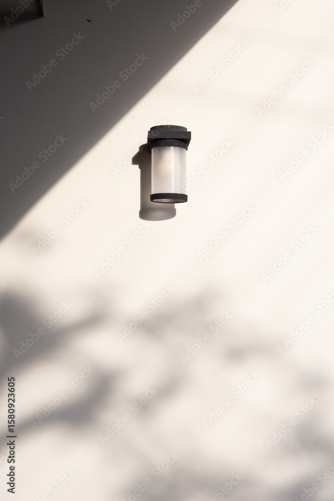 Outdoor cylinder lamp with shadow on concrete wall Outdoor cylinder lamp with shadow on concrete wall