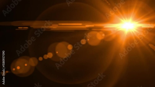 A bright golden light flare with lens effect and bokeh lights on a dark black background design element