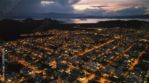 Aerial view of a city awash in a warm, inviting glow under a twilight sky, with the distant mountains and lake adding depth to the scene, Santa Catarina, California, United States.