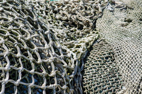 Detail view of weathered fishing nets with visible knots and intricate mesh pattern, perfect for marine, nautical, and fishing industry themes.