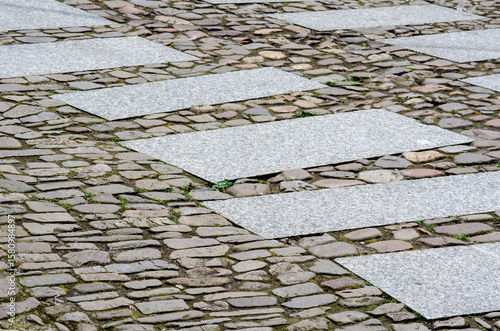 Modern granite crosswalk slabs integrated with historic cobblestone pavement, creating a unique blend of old city charm and contemporary design in an outdoor urban setting.