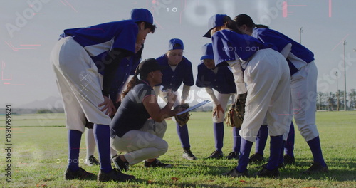 Konstfotografi Huddling softball team listening to coach kneeling with clipboard in outfield, b
