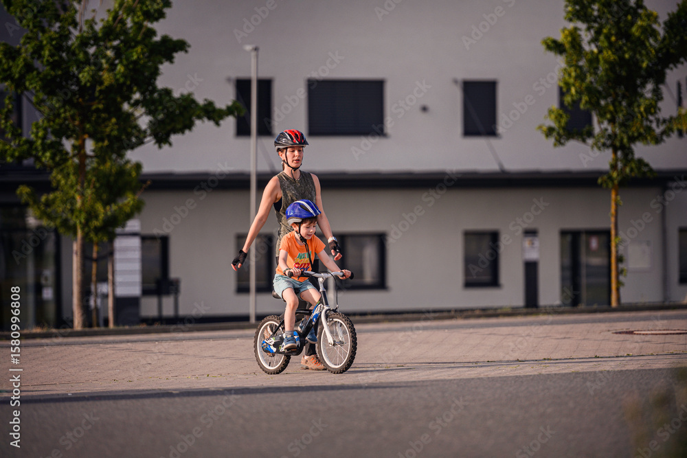 Fototapeta premium Adult Teaching Young Child to Ride Bicycle on City Street