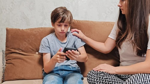 Mother lecture with teenage son over use of smartphone. Child uses phone conflict addiction. teenage boy ignores mother's request to turn off а phone.