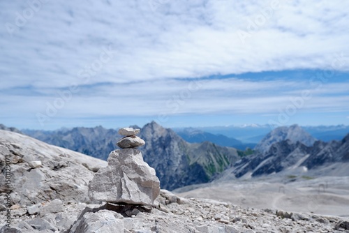 Steinmännchen auf felsigem Grat mit Blick auf Alpenpanorama und blauen Himmel