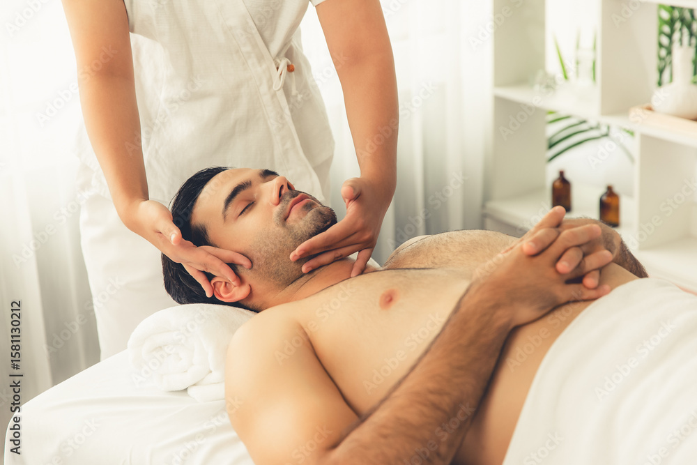 Obraz premium Caucasian man enjoying relaxing anti-stress head massage and pampering facial beauty skin recreation leisure in dayspa modern light ambient at luxury resort or hotel spa salon. Quiescent