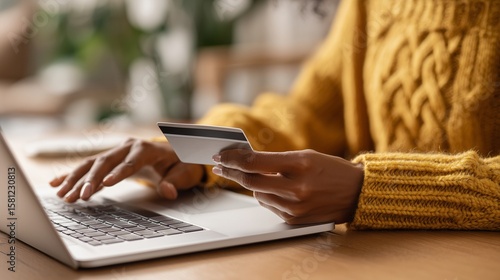 Close up of black girl hold bank credit card and type on laptop, shopping online using computer, buying goods or ordering online, entering bank accounts and details in online banking offer