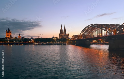 Cologne Cathedral and Hohenzollern Bridge over Rhine River at sunset, Germany