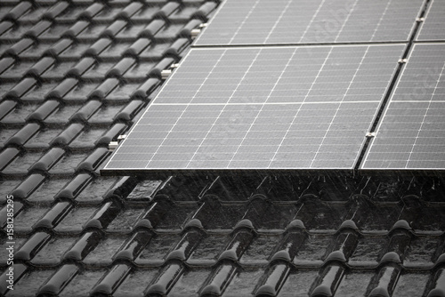 Corner of solar panel array on tiled roof in heavy rain  
