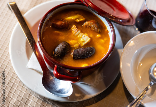 Φωτογραφία In deep baking dish there is portion of Asturian fabada - thick soup of beans, smoked bacon and spices