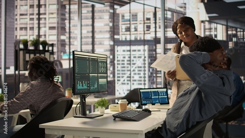 Картината върху платно Black male CEO dealing with back pain and stretching his muscles at the desk, sitting with an incorrect posture and trying to fix it