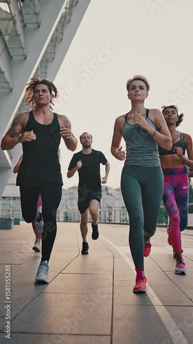 Running club. Multiracial team of like-minded people running through the city streets. People in sports uniforms and shoes have a group workout