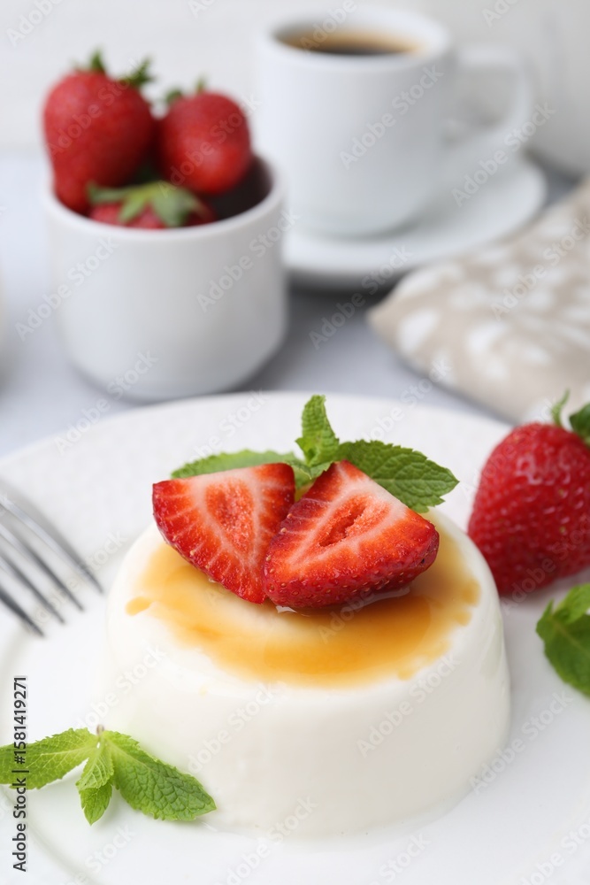Tasty panna cotta with caramel, strawberries, mint and coffee on table, closeup Tasty panna cotta with caramel, strawberries, mint and coffee on table, closeup