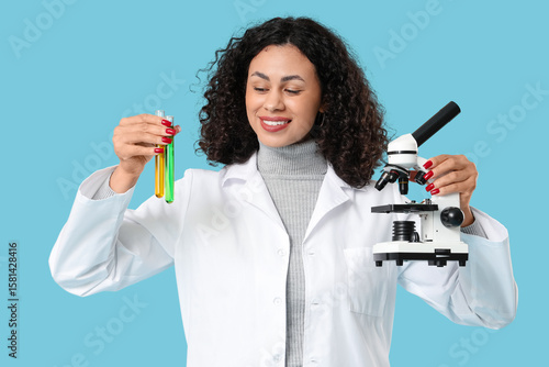 Female African-American scientist with microscope and test tubes on blue back...